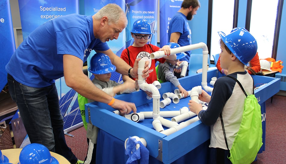 engineer assisting children with STEM activity