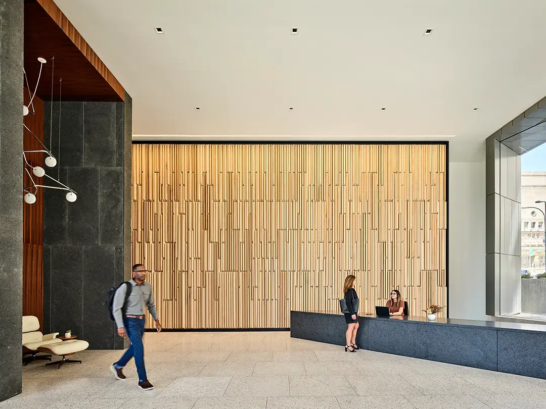 feature wall in corporate lobby made of wood slats, serving as background for reception desk and casual seating area