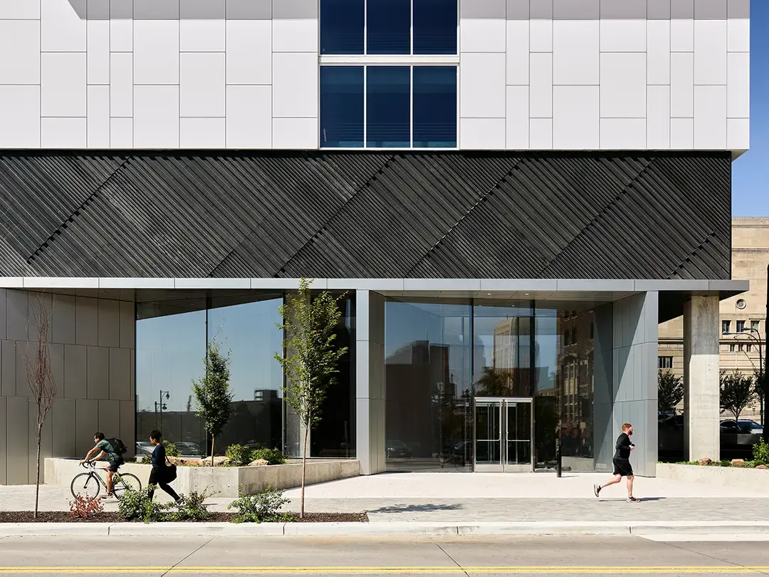 view of corporate headquarters building entrance from across street, with cyclist and pedestrians passing by