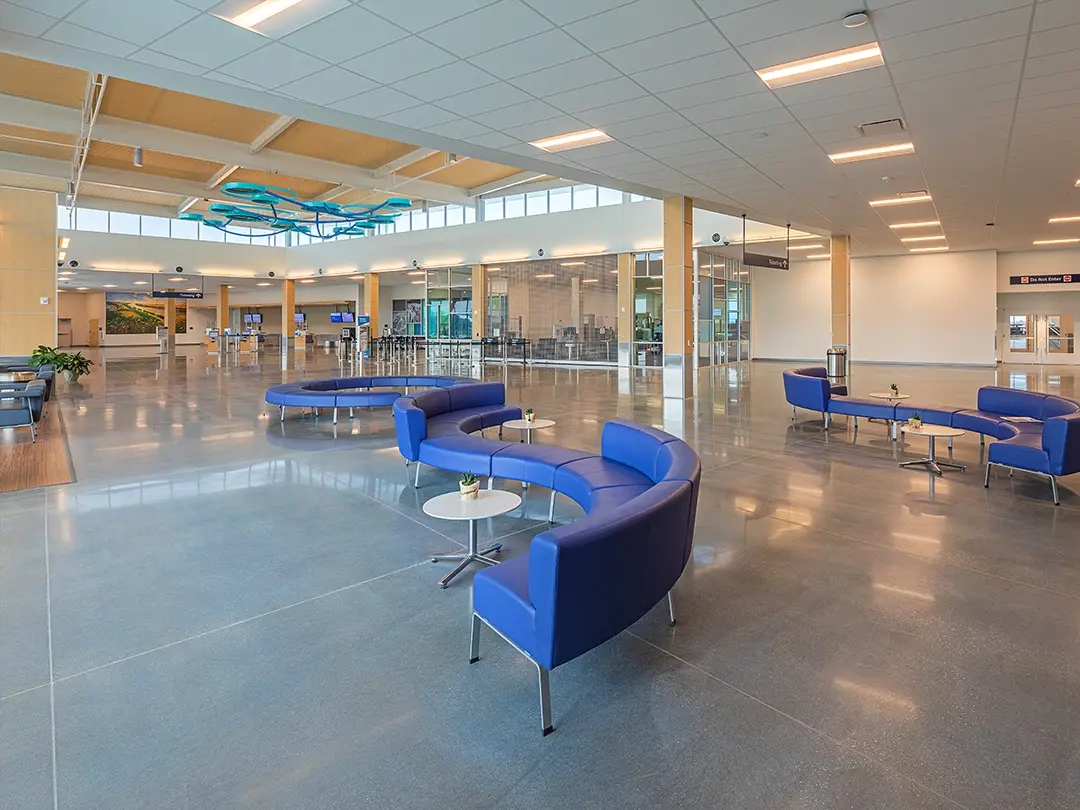 airport entry space with curved seating areas, overhead sculpture and clerestory windows