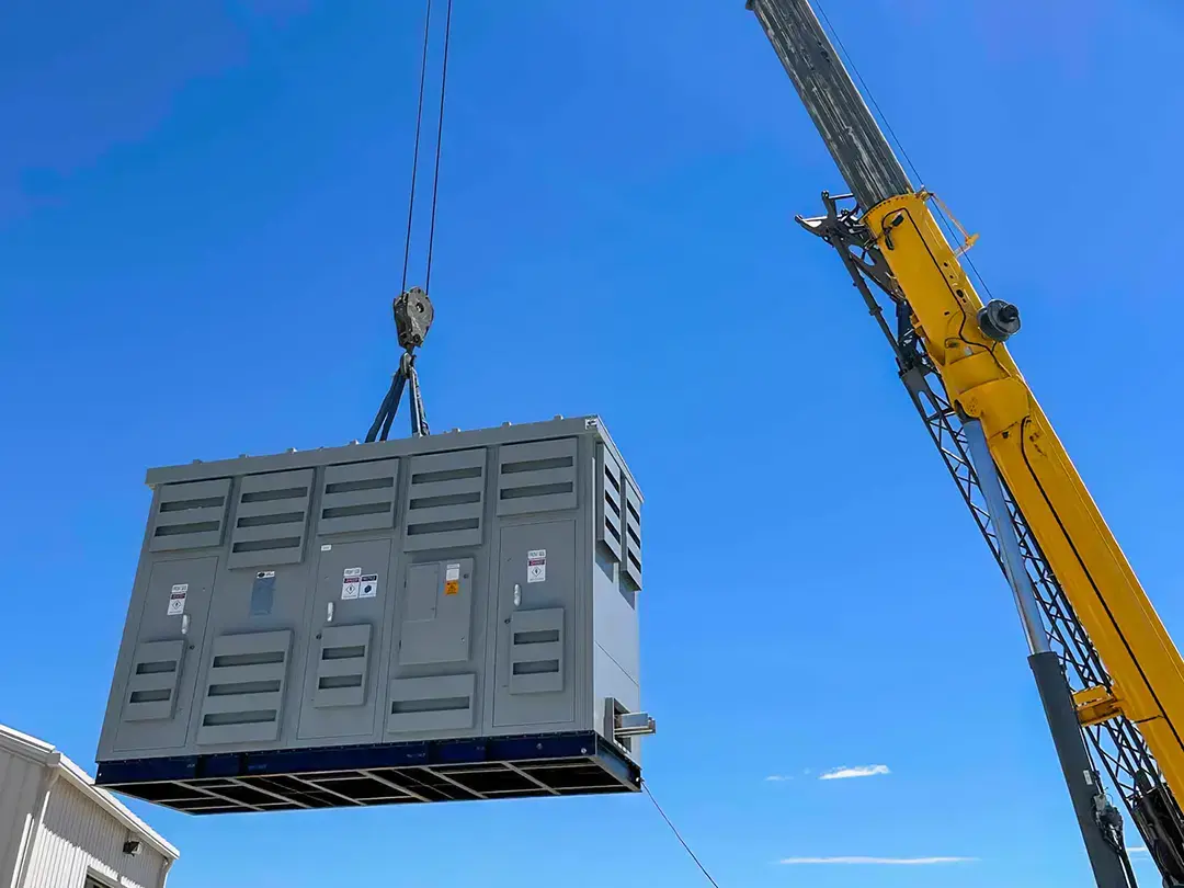 crane lifting battery storage unit on site