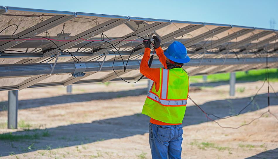 construction worker connects cables on solar array