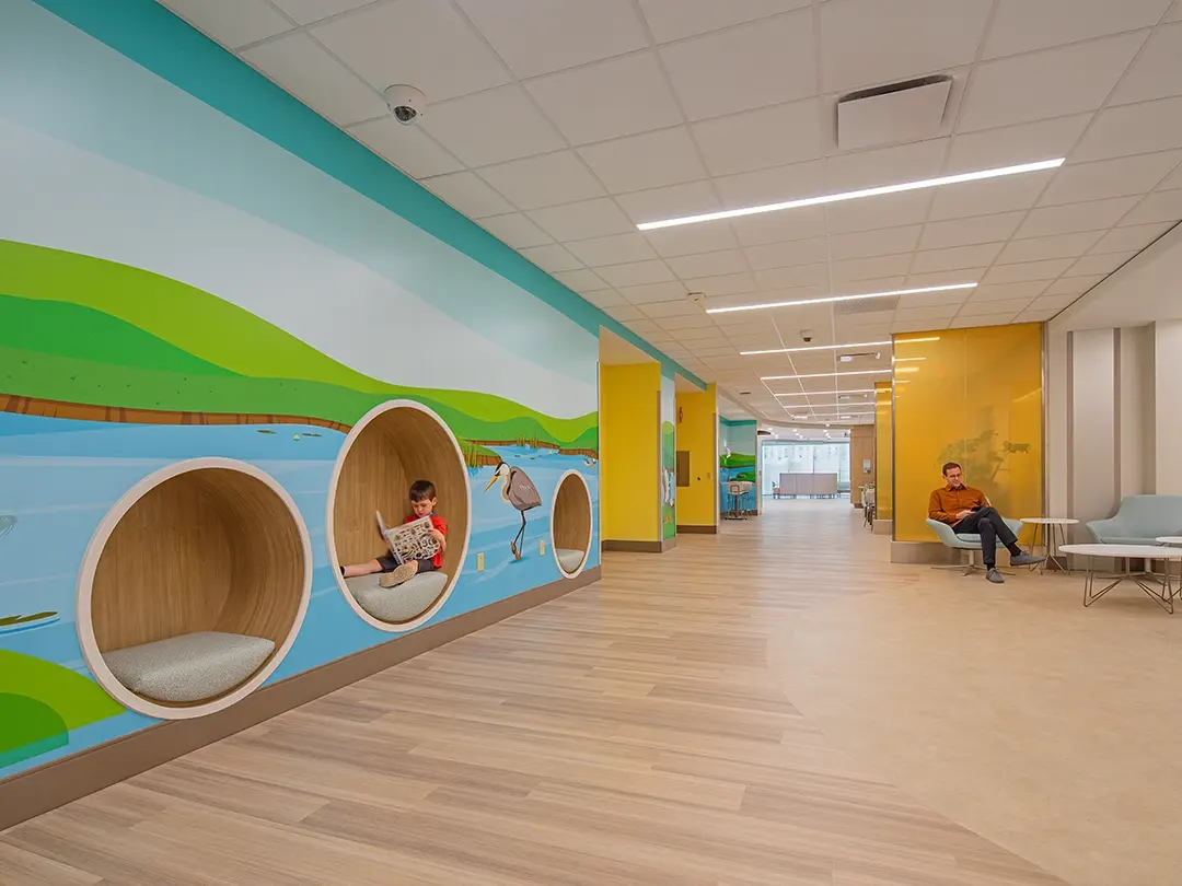 hospital waiting area with round nook seating for children, colorful nature wall murals and adult seating
