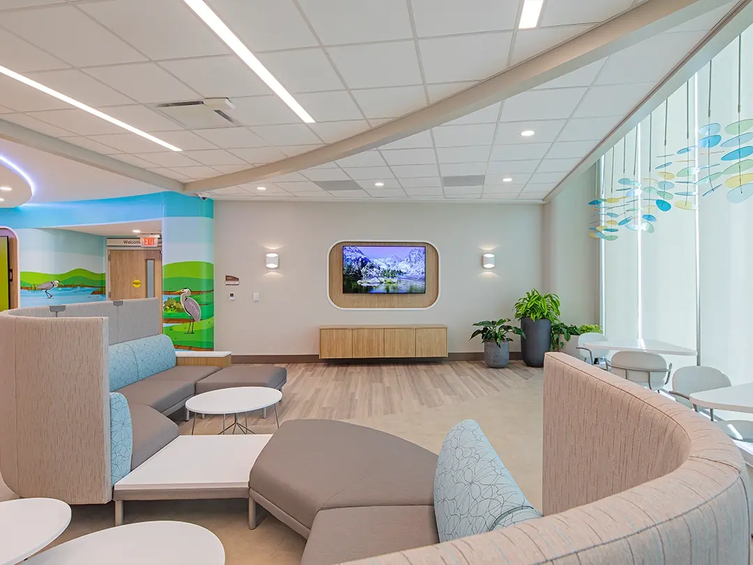 hospital waiting area with colorful nature mural, couches and television