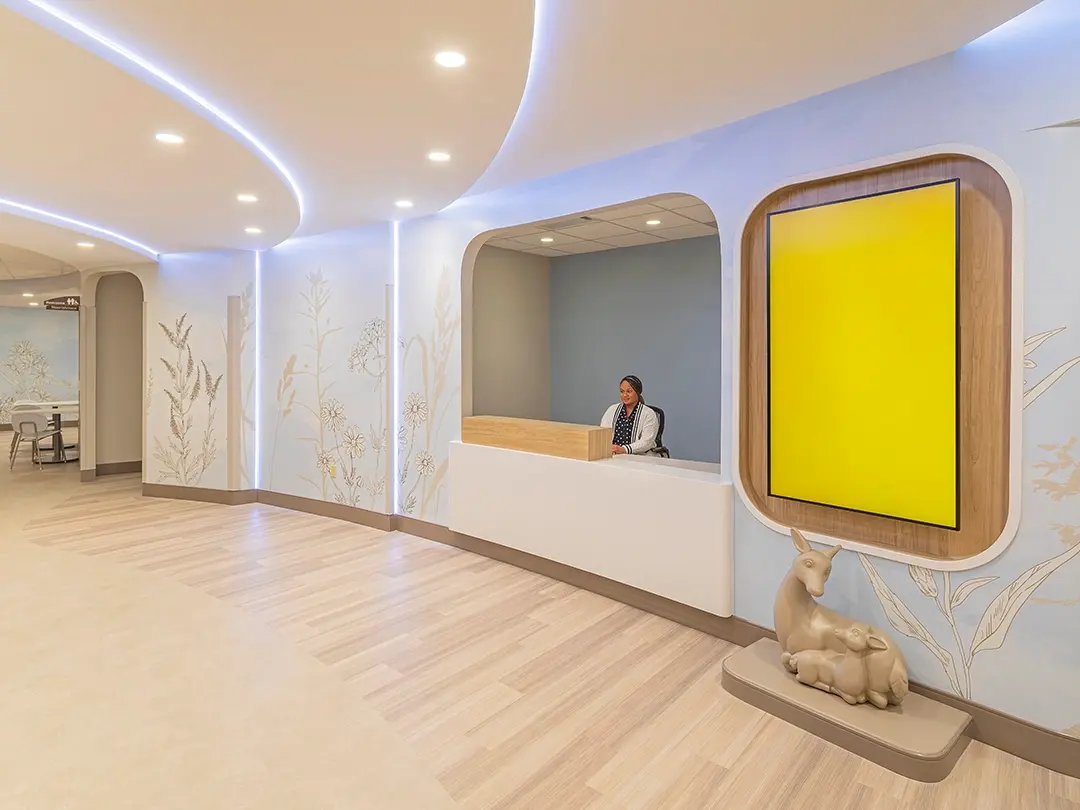 hospital reception desk with plant murals on wall and sculpture of doe and fawn