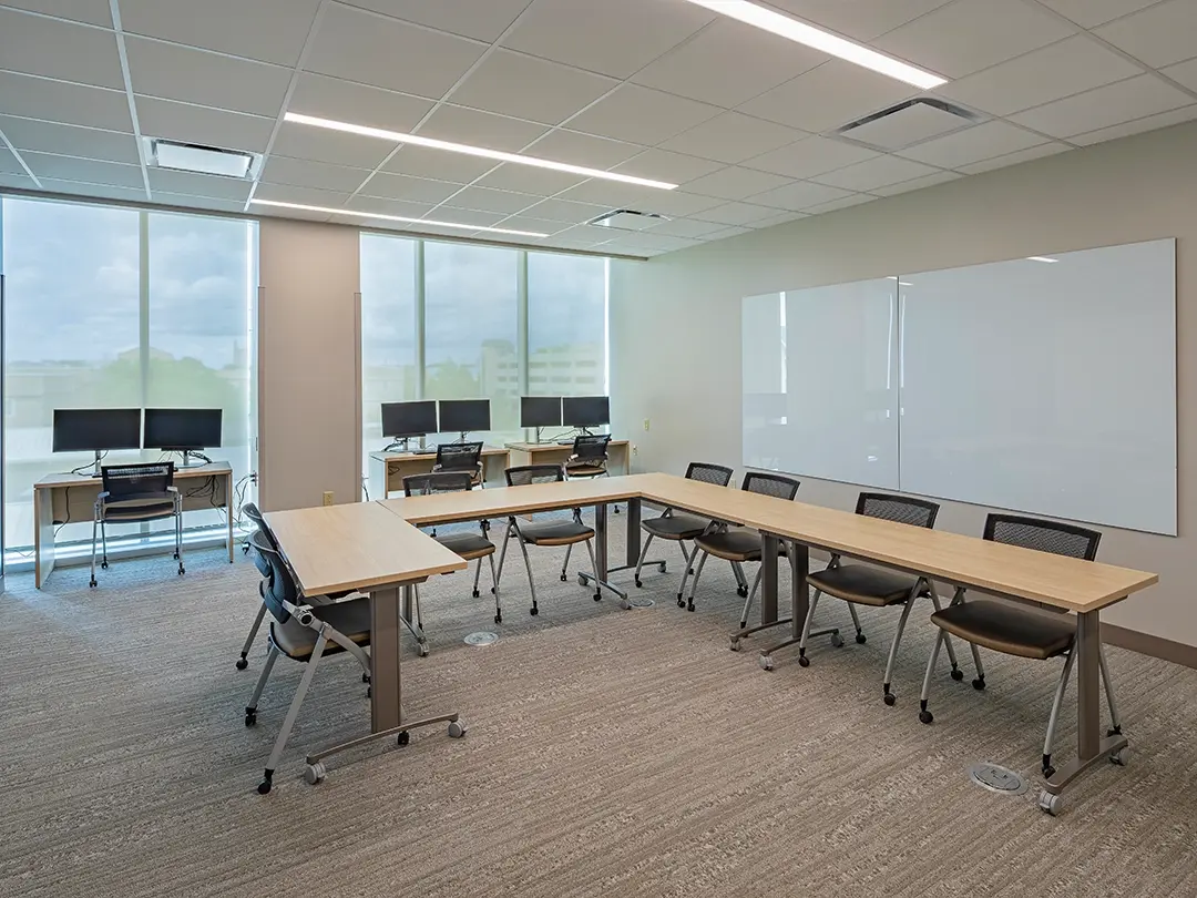 conference room with table, chairs, desks with monitors, white board