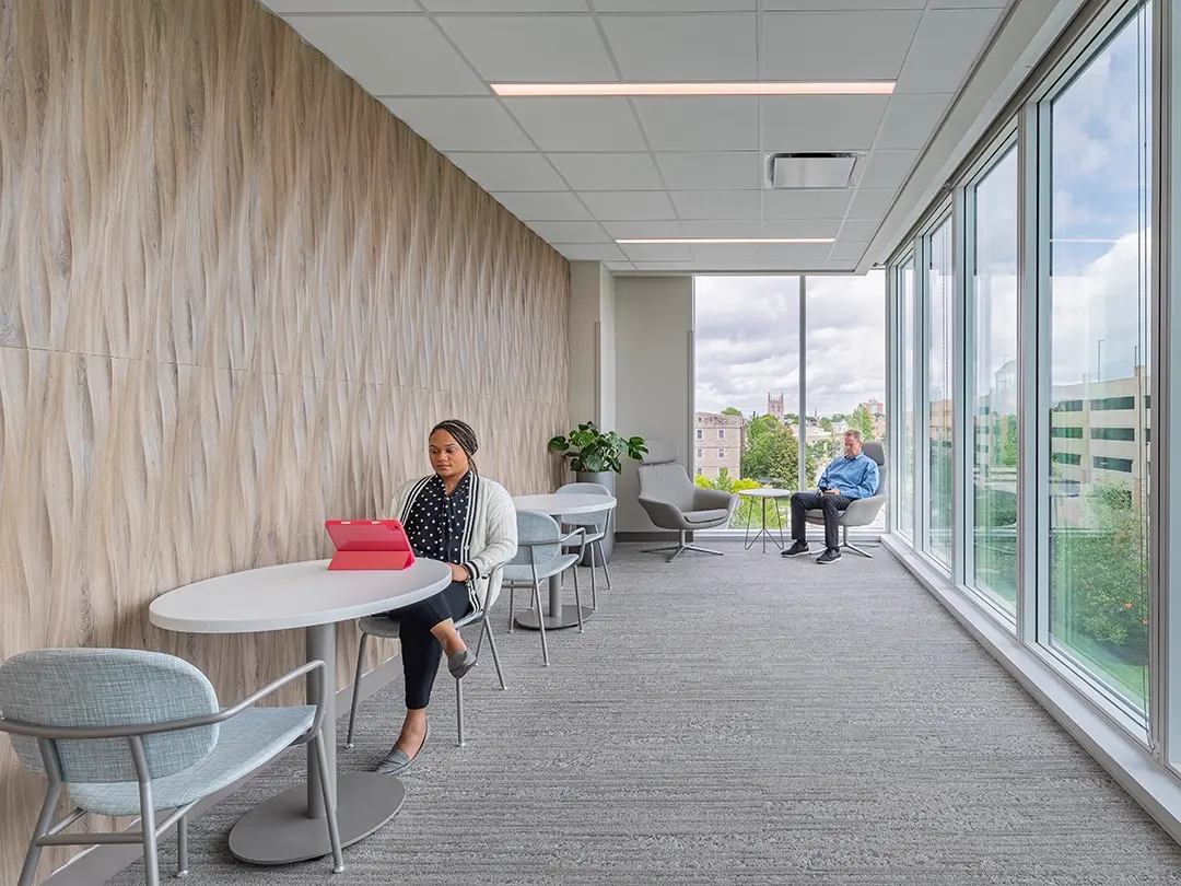 quiet lounge area in hospital with tables and seating, large windows