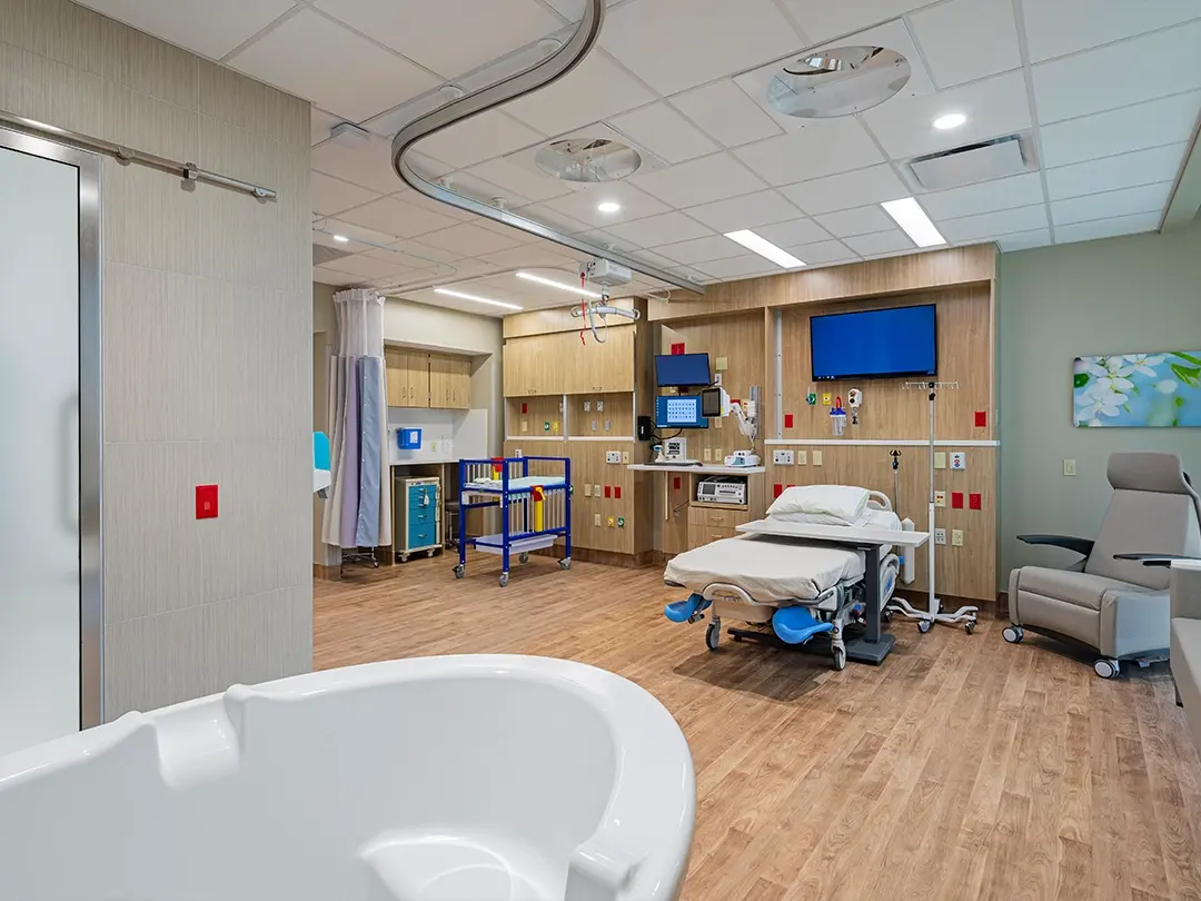 birthing room with bed, tub, infant bed
