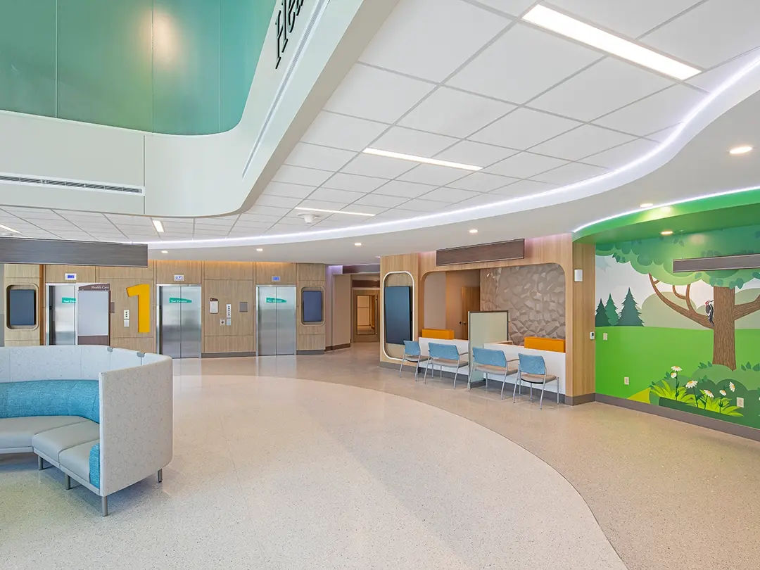 elevator lobby area with reception desk, colorful mural, couch seating