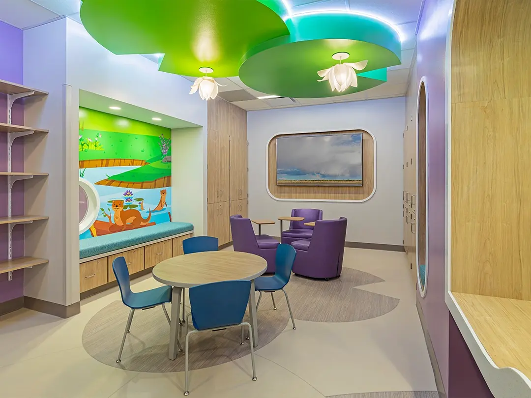 child-friendly waiting area with otter mural, flower lights, television, table, chairs, desks 