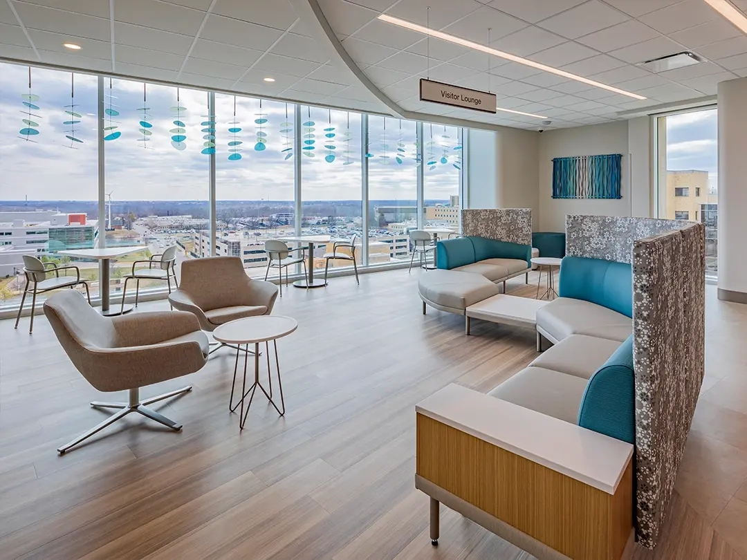 hospital visitor lounge with seating groups, large windows, hanging artwork
