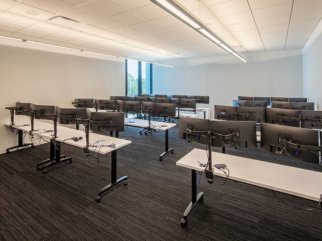 room with tables and multiple two-screen workstations