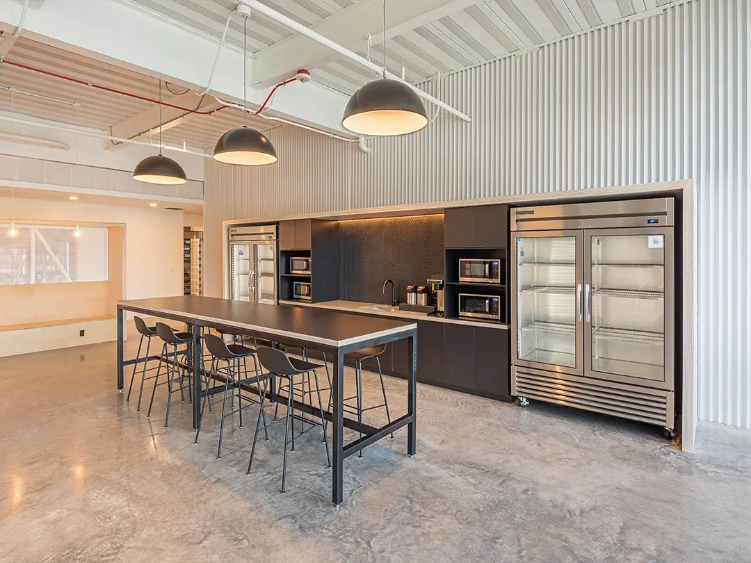 employee break room with high table, microwaves, refrigerators and sink counter