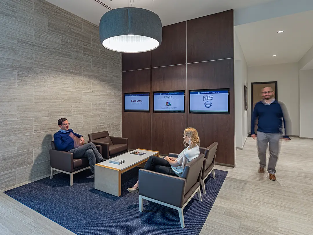 people in sitting area of office with video screens on wall