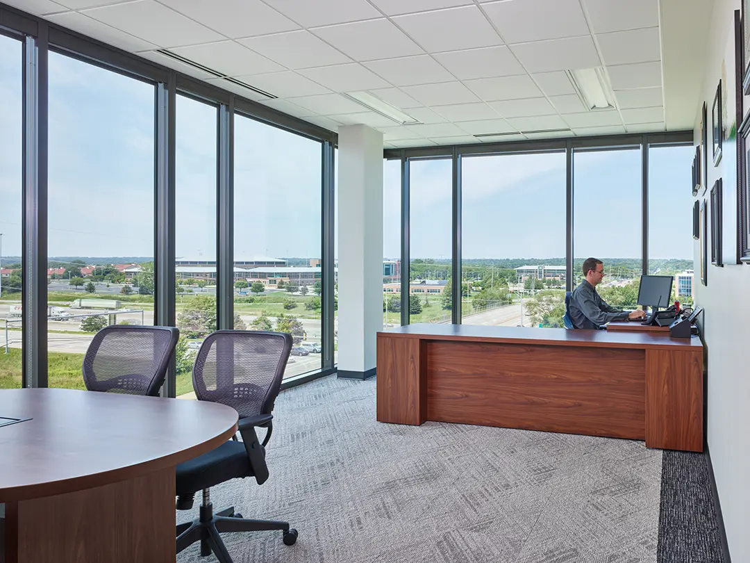 worker at desk in office with conference table in foreground 