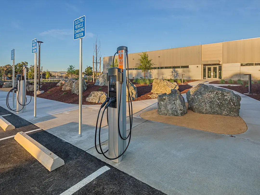 electric vehicle (EV) charging stations in parking area at building entrance, with large boulder landscaping