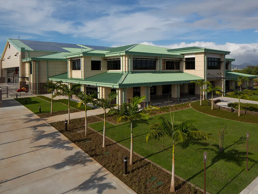 exterior view of facility with green roof and palm trees