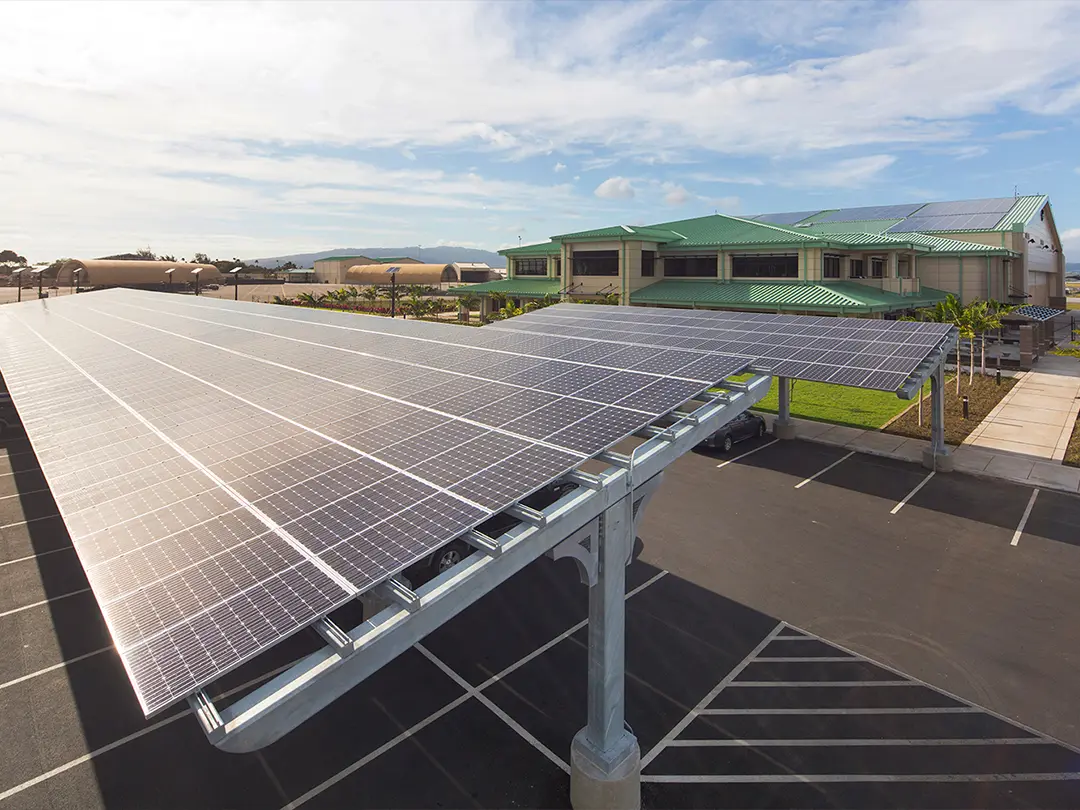 solar panels over parking lot spaces with facility in background
