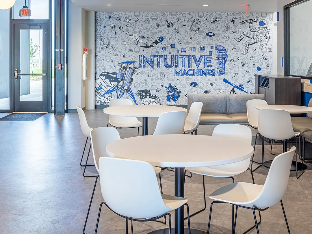 casual table/chair seating with background of wall mural that includes company logo built by descriptive words and drawings of space theme