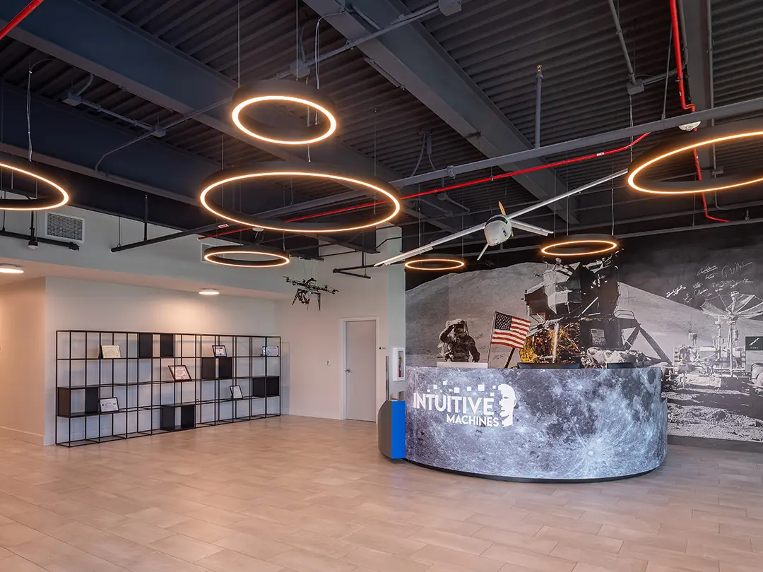 reception desk with moon landing image wall, shelving and spacecraft models hanging overhead, amongst light rings