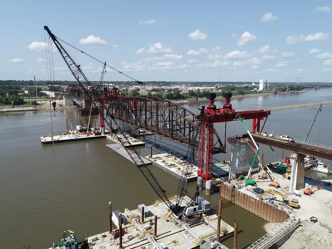 cranes and barges placing bridge spans on river