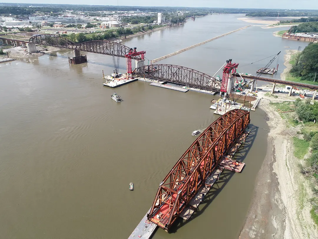 aerial view of cranes and barges placing bridge spans on river