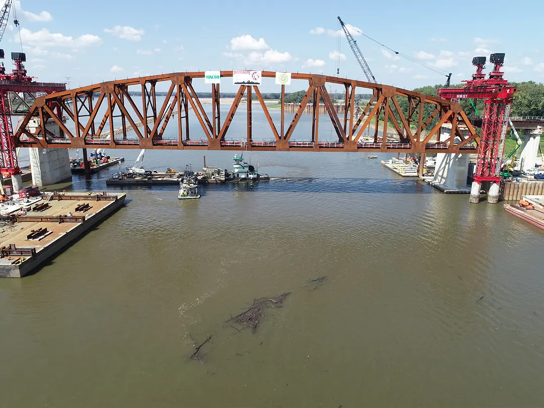bridge span in place with construction barges below in river