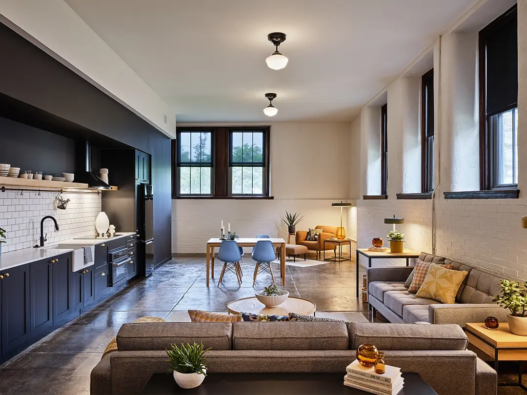 apartment layout with kitchen wall cabinetry, couch seating area, dining table and chairs, and private chair seating