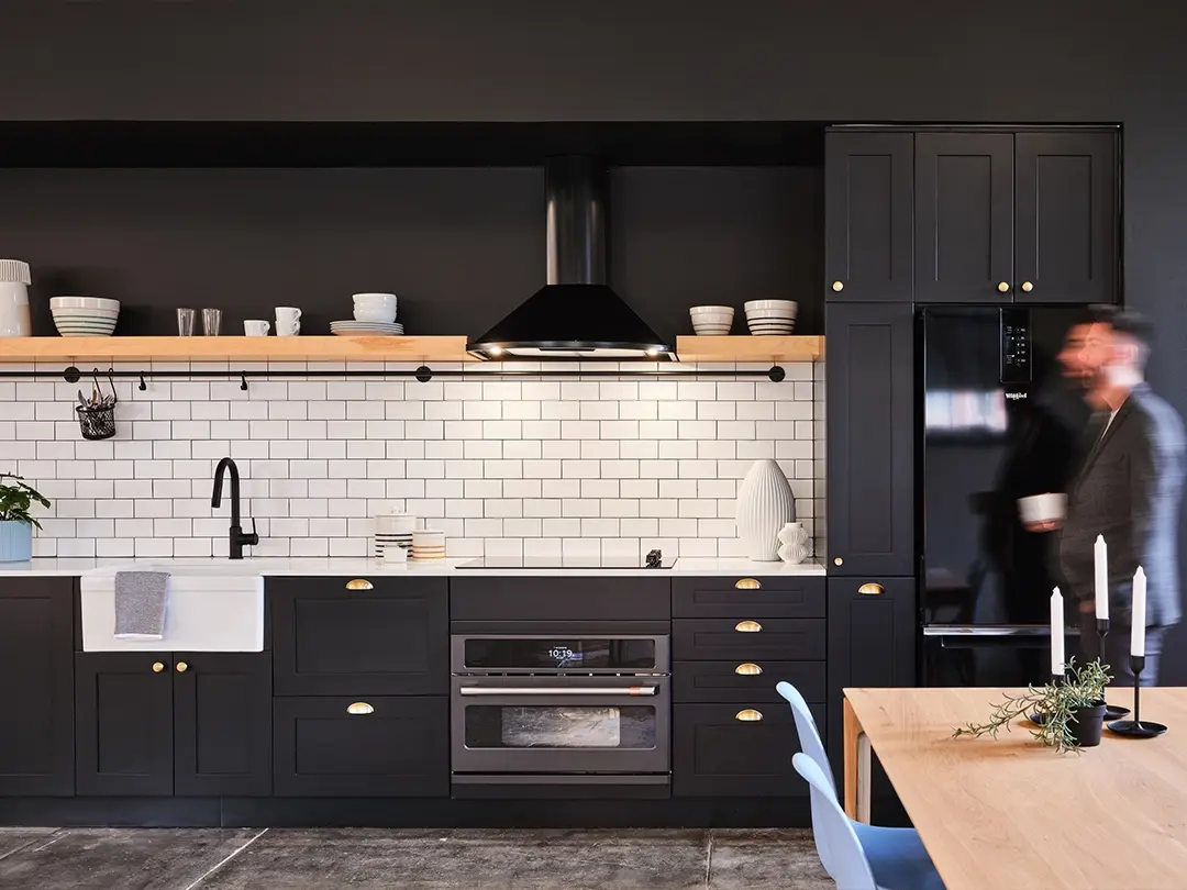 apartment kitchen featuring black cabinetry and appliances, white sink and white backsplash subway tile