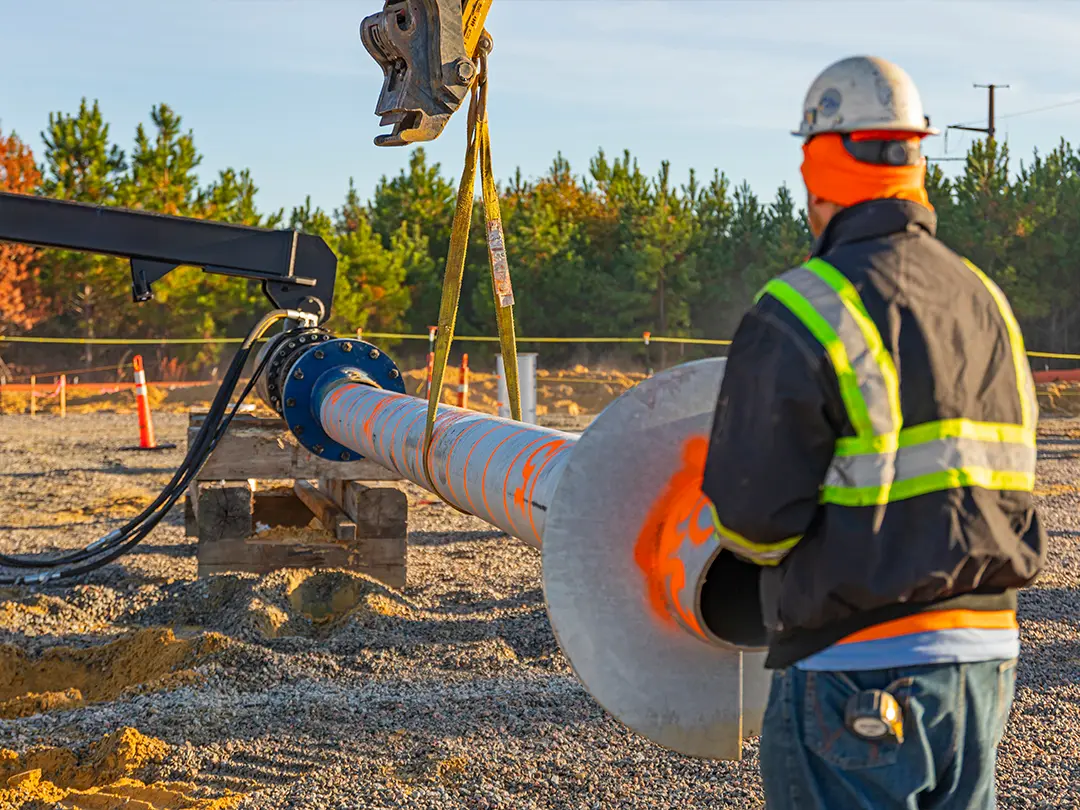 worker guides equipment placement on construction site