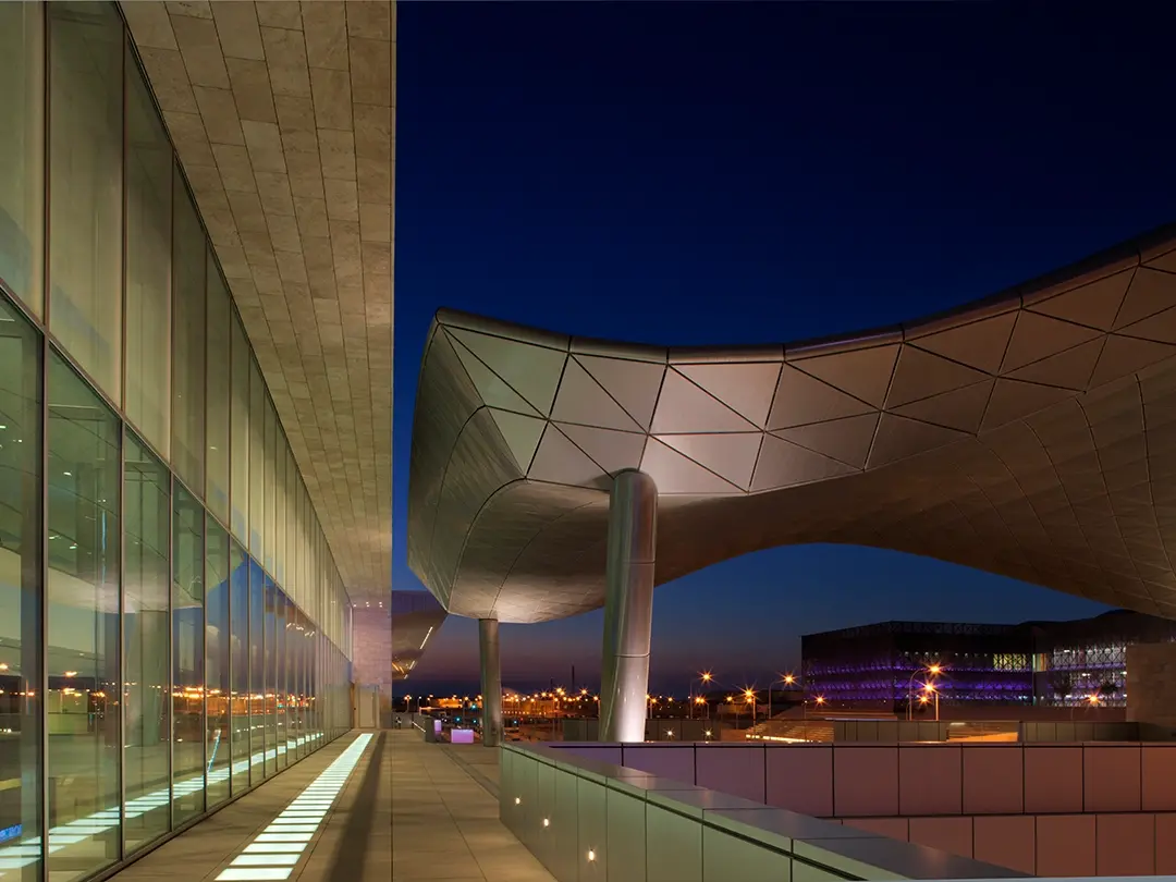approach to covered gathering space outside convention center, at night