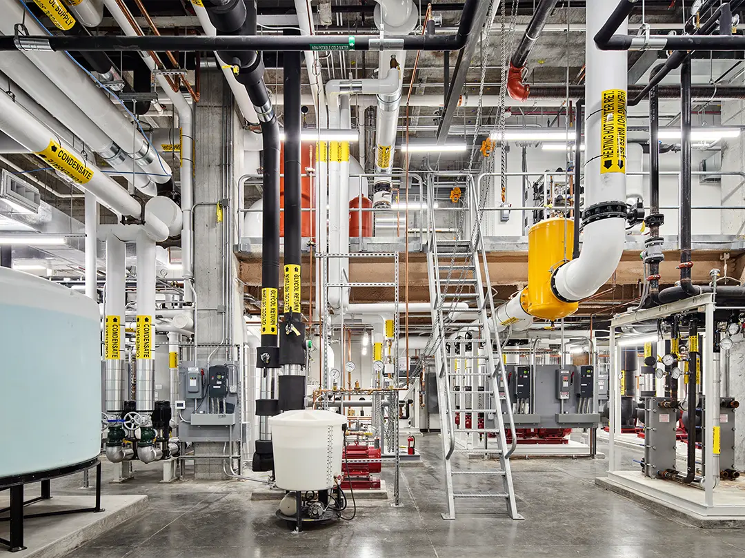 complex equipment room with piping, ladder and liquid storage tanks 