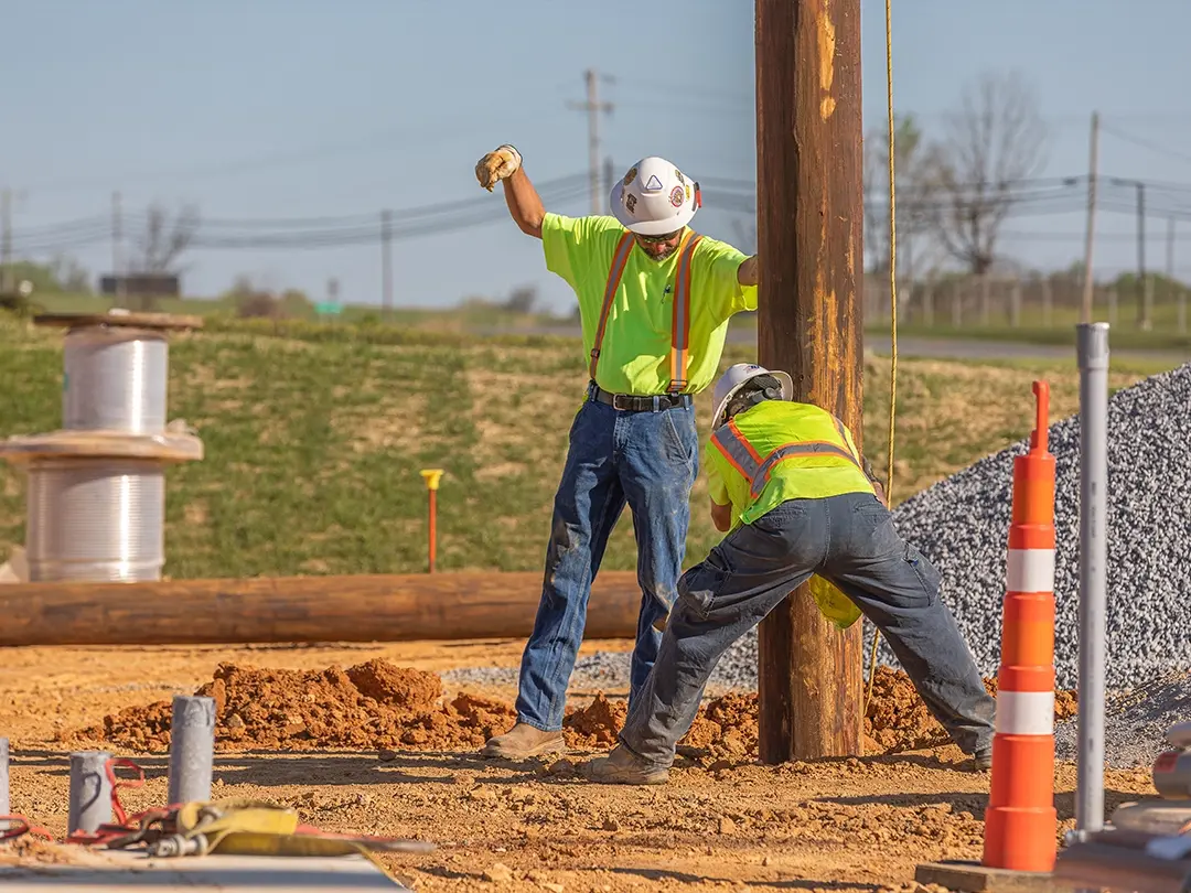 construction workers setting wooden pole