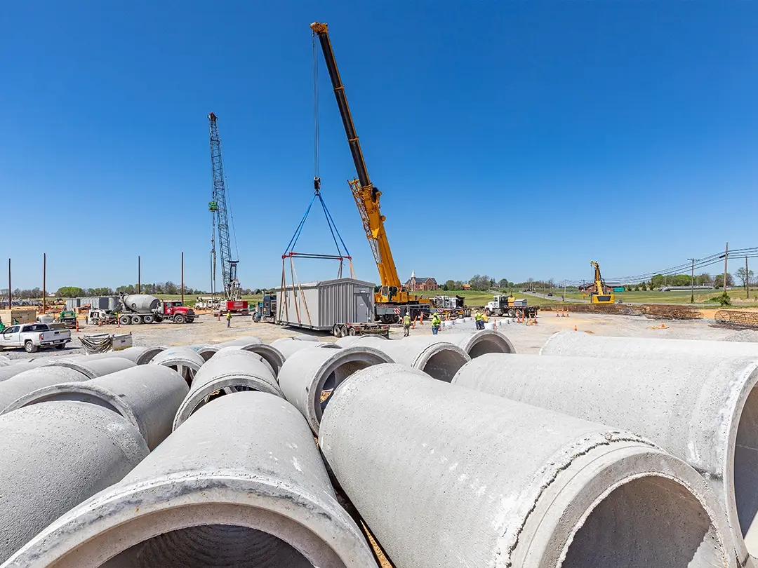 concrete piping in foreground with crane setting substation building in background