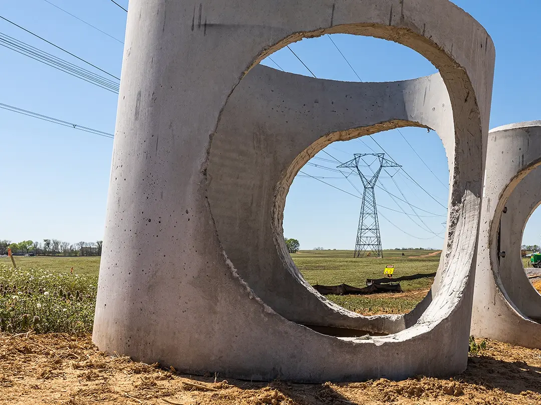 lattice transmission towers viewed through holes in concrete piping components