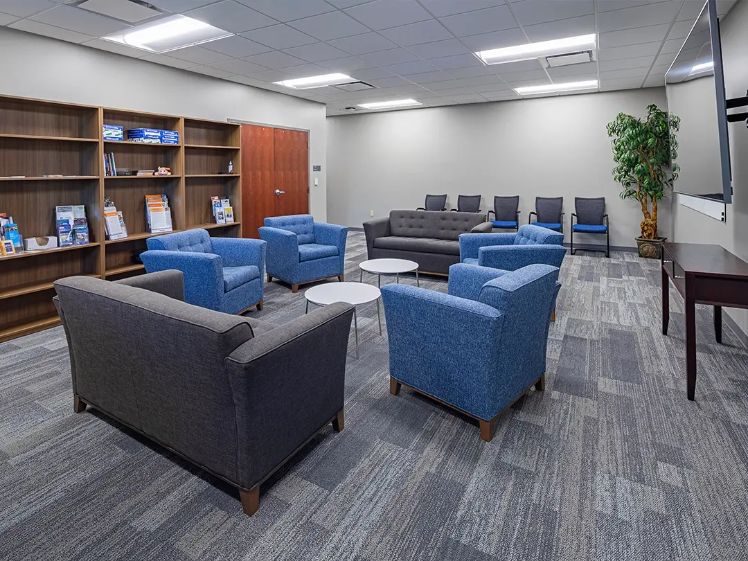comfortable seating area with chairs, couches, bookshelves and LCD screen