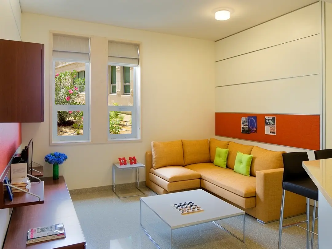student room with couch, desk and bar, window overlooking garden
