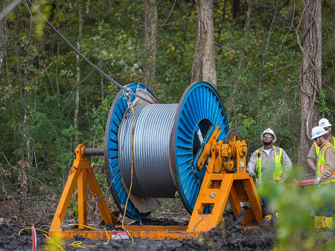 workers with spool of cable being strung