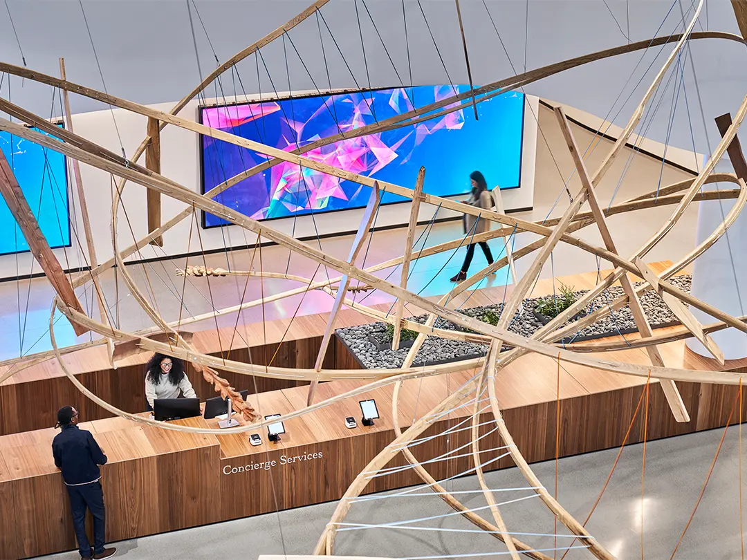 view from above looking down at concierge desk through hanging sculpture, with large artwork on wall in background