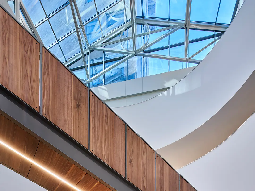 view looking up to lobby skylight windows with wood-clad staircase