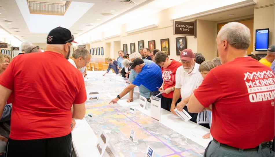 small crowd reviews available maps and documents on table at public meeting