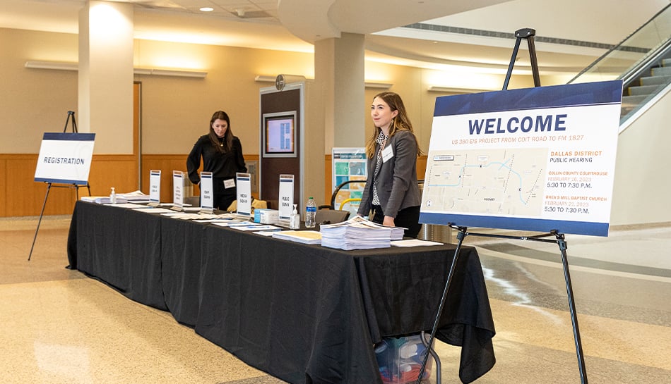 team members staff welcome table at public meeting