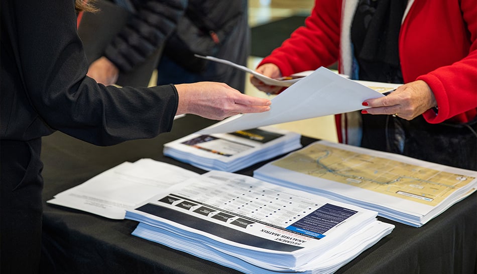 closeup of people handling paper handouts at public meeting