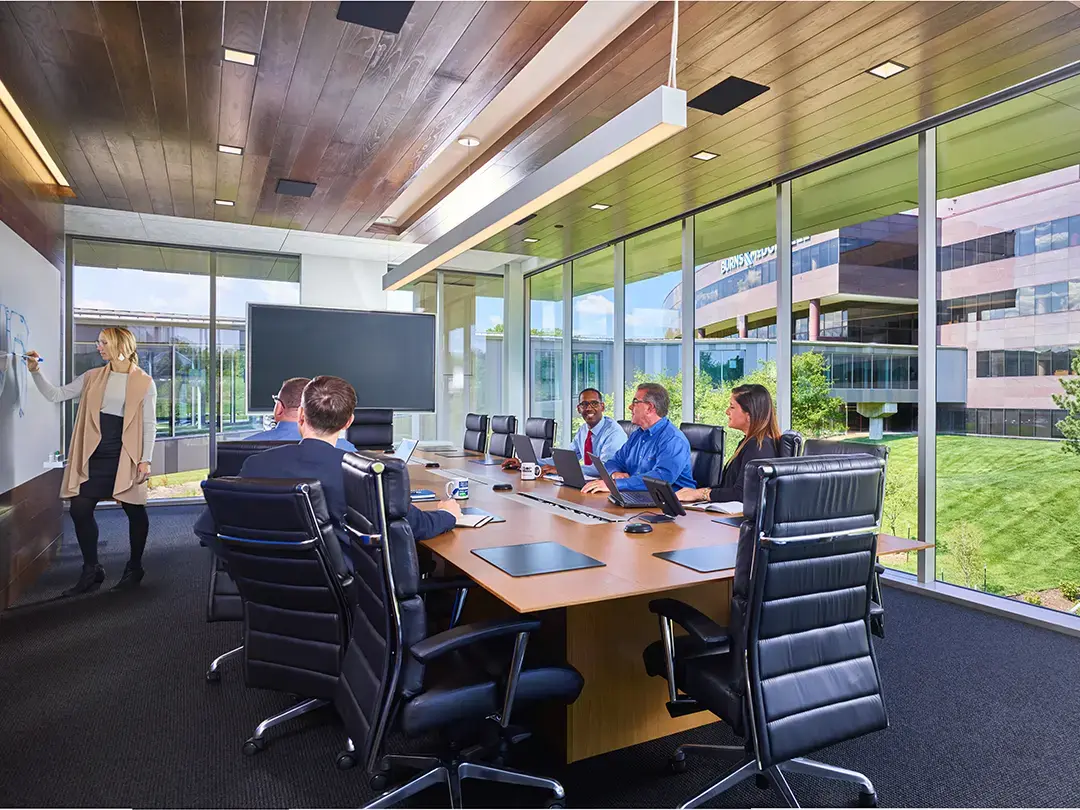 team collaborating in conference room with green space outside windows