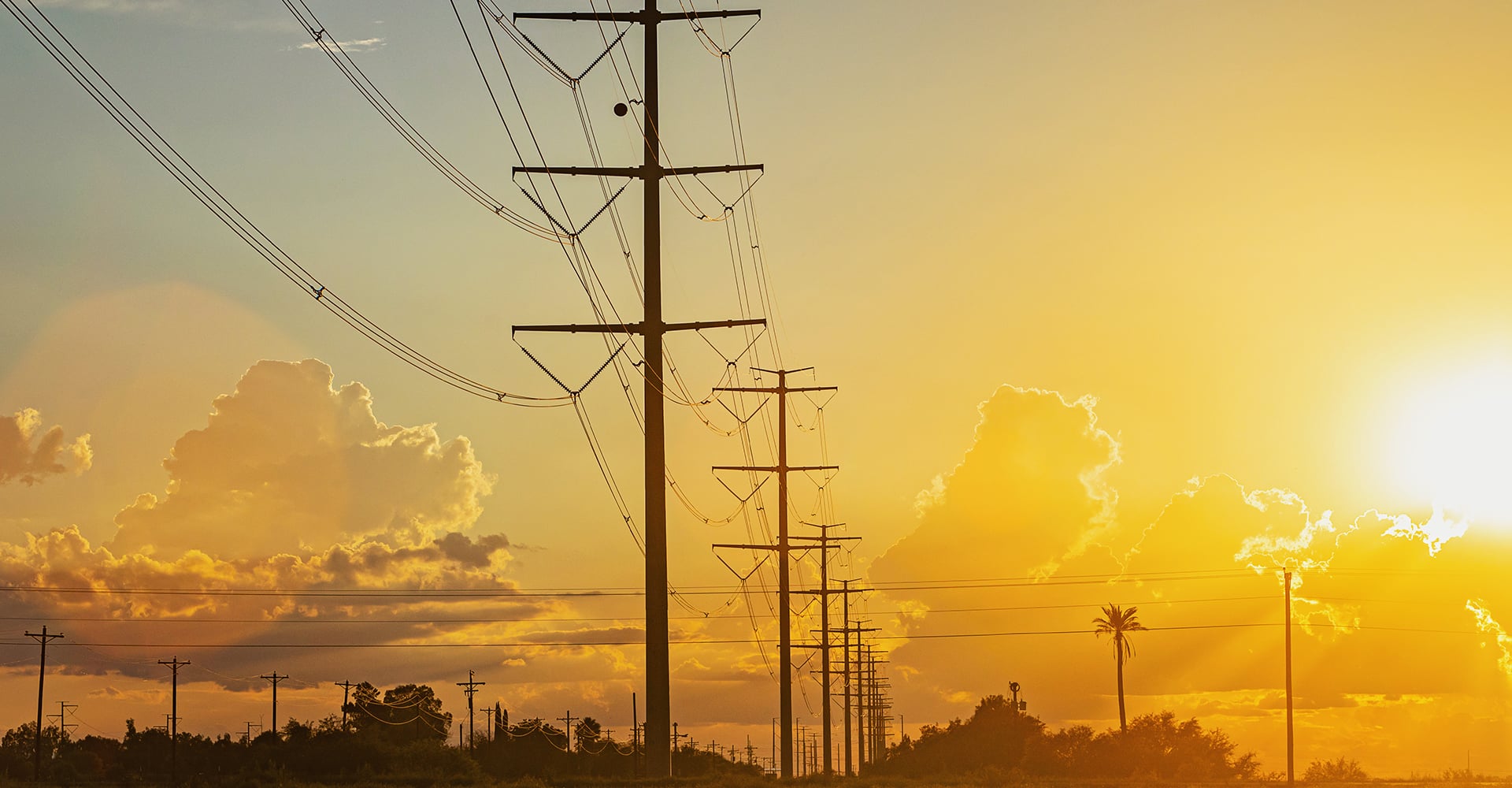 electrical transmission lines with yellow sky and sun in background