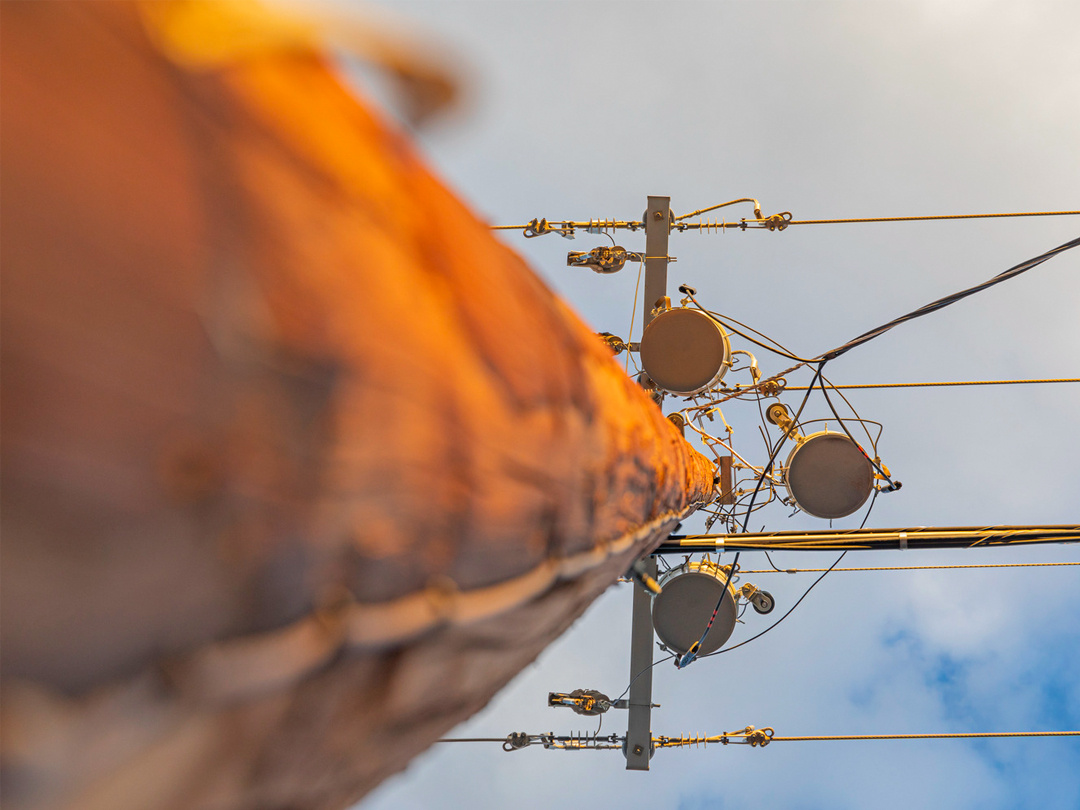 view from ground looking up to equipment at top of wooden power pole